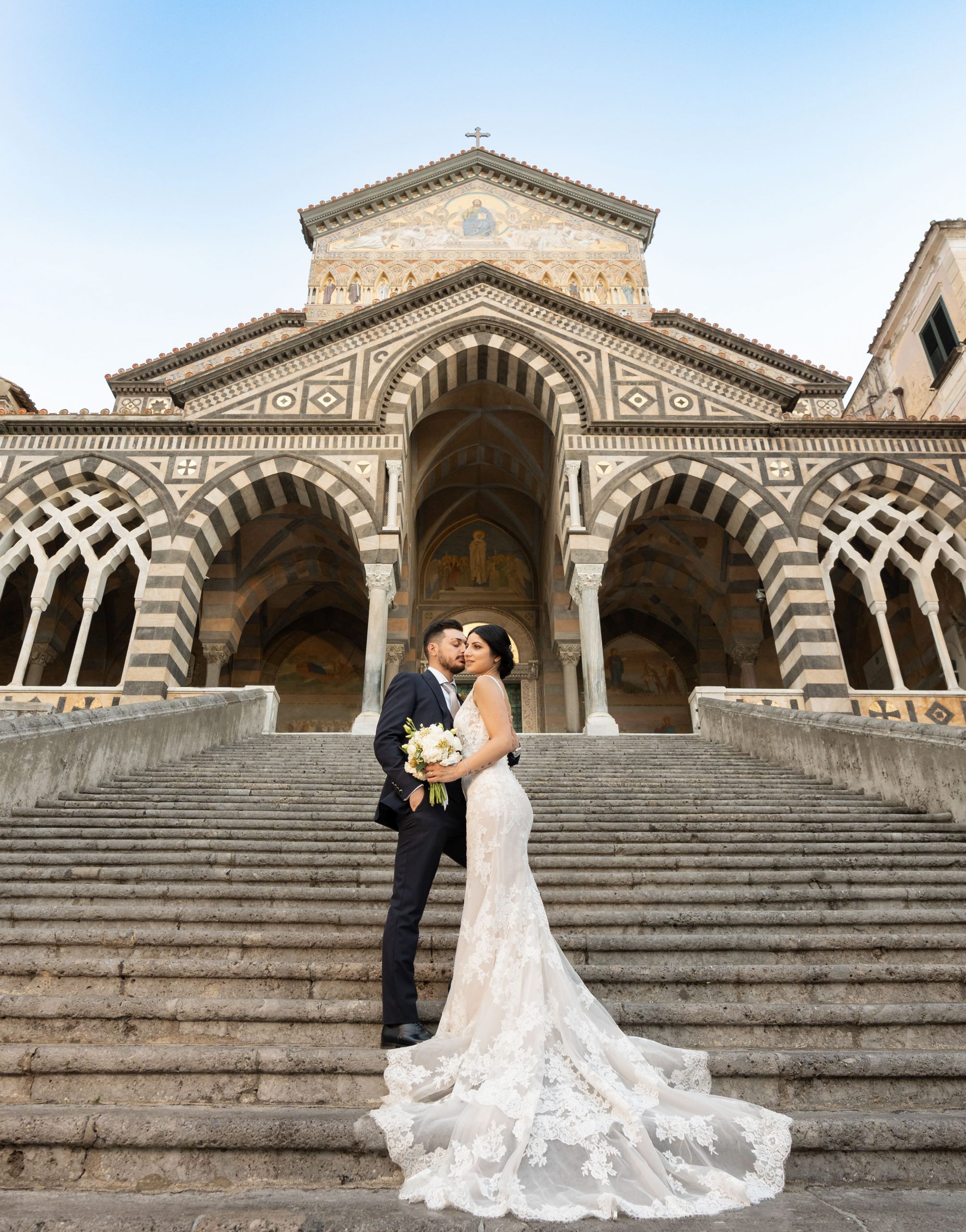 Bride and groom share a romantic moment on the grand staircase of Amalfi Cathedral, capturing the beauty of an unforgettable wedding in Amalfi.